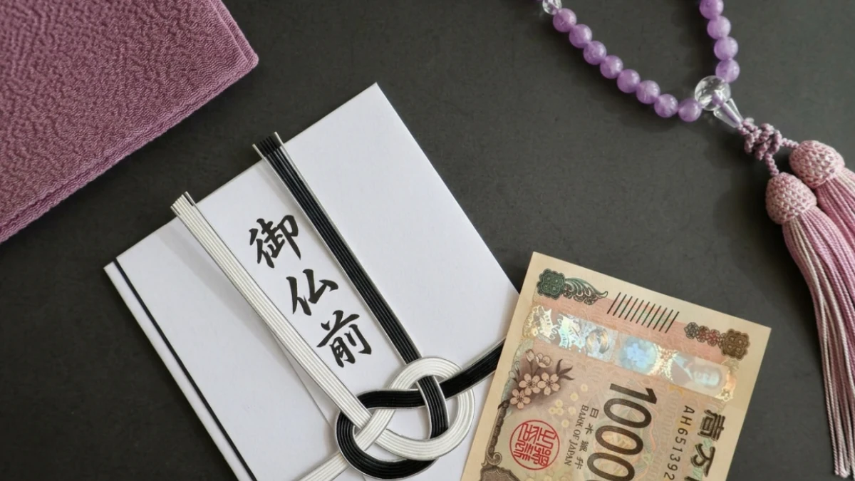 御仏前と書かれた不祝儀袋と一万円札、数珠が並ぶ、四十九日法要の香典を準備した仏事の場面