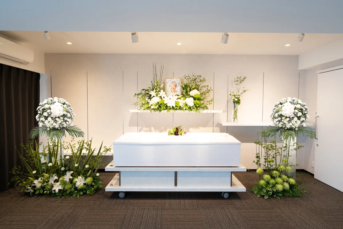 想送庵カノンの祭壇装飾事例、白百合とグリーンで整えた白い祭壇と棺。左右に供花のスタンドを配して