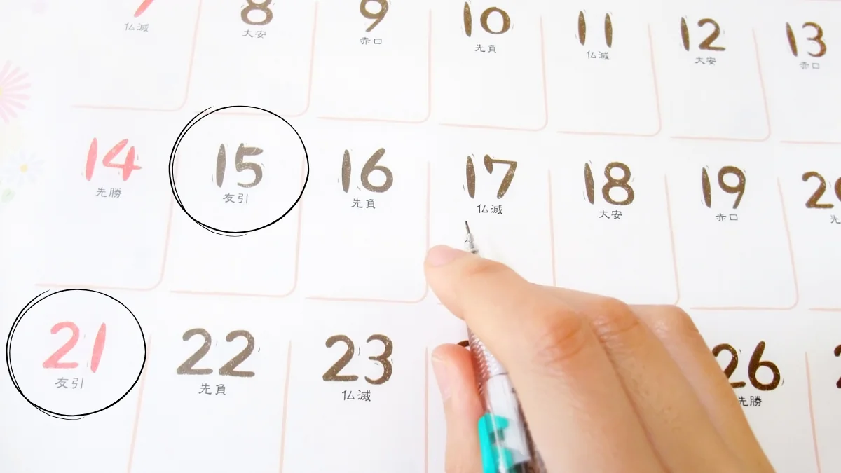 六曜入りカレンダーの友引の日に丸印を付けて葬儀日程を選ぶ様子
