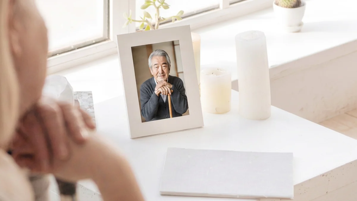 窓辺に飾られた遺影写真とキャンドルを静かに見つめるご家族の様子