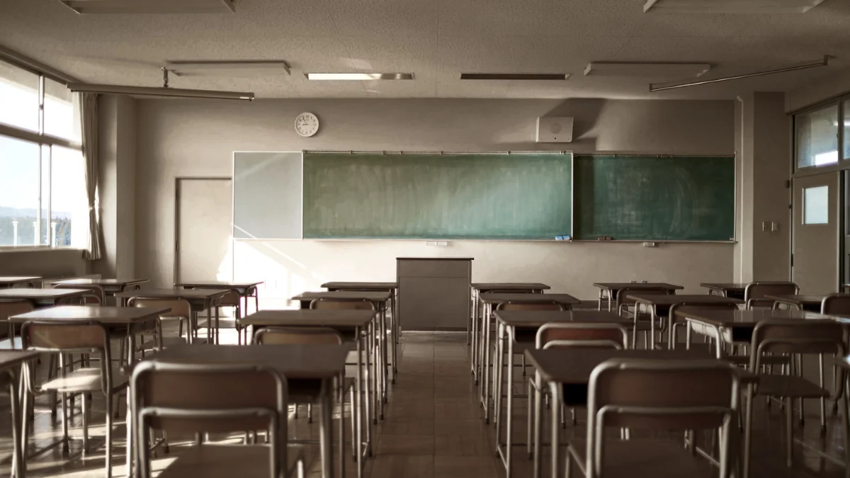 誰もいない教室に机と椅子が並び、窓から光が差し込む静かな情景