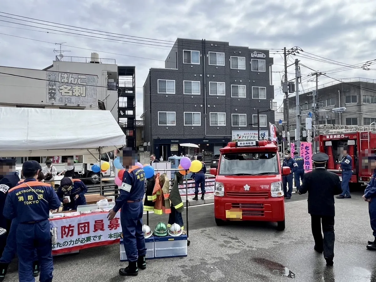 かつしかさくら祭りの消防団員募集の会場。ポンプ積載車の前に子ども用の防火服とヘルメットが並び、消防団員が来場者を迎えている