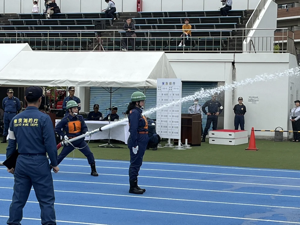 本田消防団の消防操法大会で、競技場のトラックに立ち、ホースを構えて目標に放水する消防団員