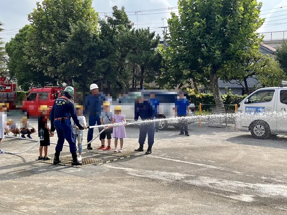 葛飾区立葛飾小学校の防災訓練で、消防団員と一緒に消火栓のホースから放水する児童たち