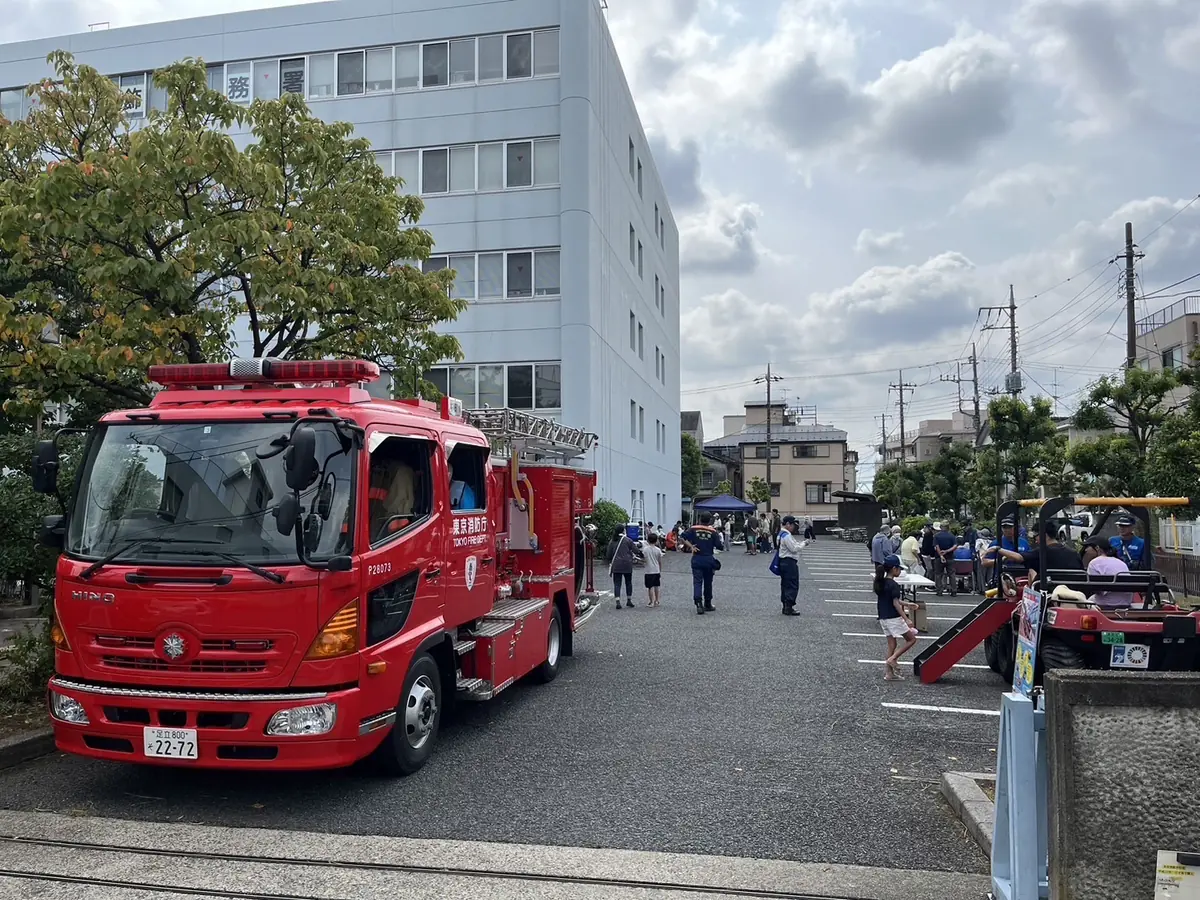 立石宮元町会の防災訓練の会場。駐車場に消防車が止まり、奥で訓練の準備が進んでいる