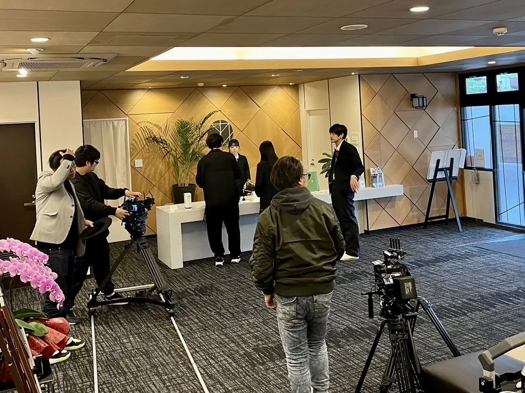 想送庵カノンの受付前で行われた啓発動画の撮影風景。カメラと三脚が並び、撮影スタッフと出演者が受付台の周りで準備している